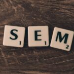 Wooden background with letter tiles spelling SEM, representing search engine marketing.